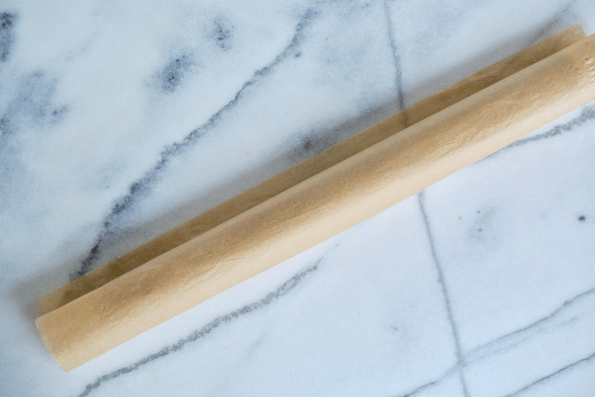 The parchment wrapped cylinder of cranberry filled sourdough pastry.