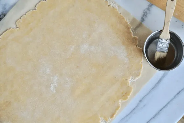 Bush the edges of the sourdough pastry with water.