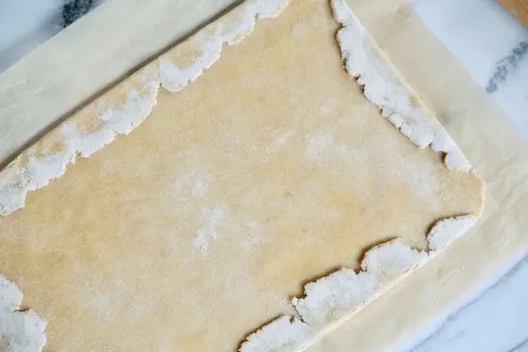 Folding the ragged sourdough pastry edges over to form a straight sided rectangle.