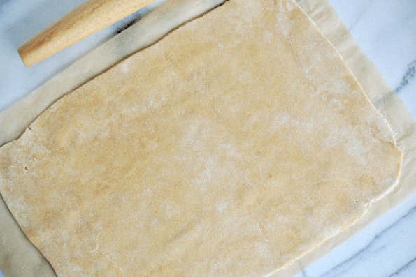 Rolling the sealed sourdough pastry edges to 1/4 inch thickness.