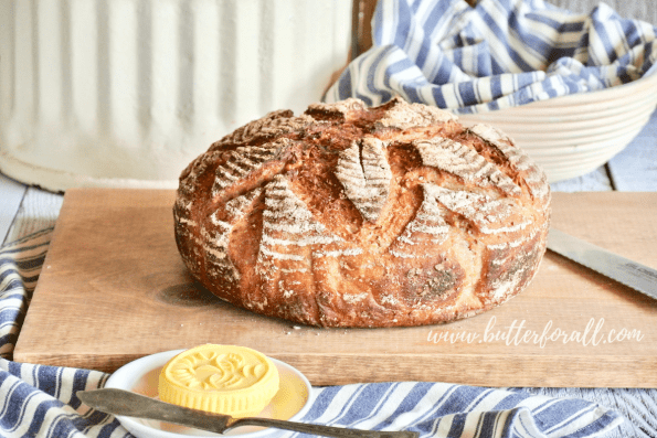 A tall boule of fresh whole grain sourdough bread perfect for eating with raw butter.