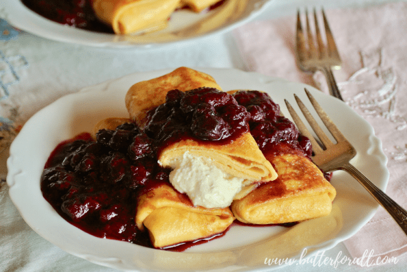 A plate of hot sourdough blintzes topped with berry compote.