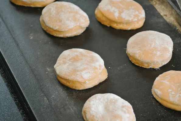 Cooking the English muffins on a cast-iron griddle.