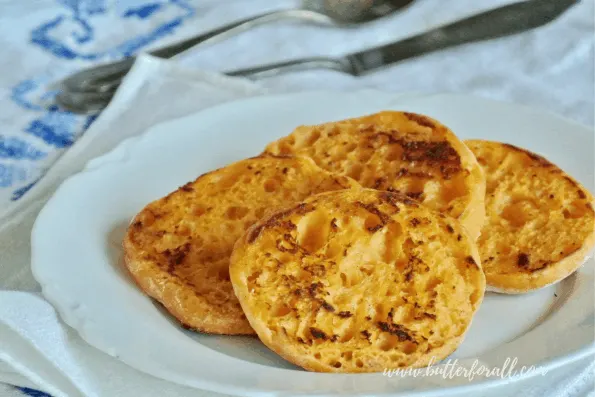 A plate of toasted sweet potato sourdough English muffins with tons of nooks and crannies just waiting to be slathered with real butter.