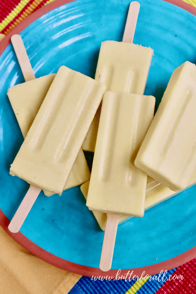 A colorful plate of frosty probiotic coconut mango lassi popsicles.