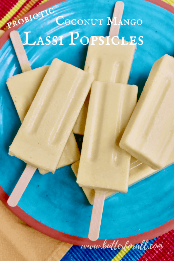 A colorful plate of frosty probiotic coconut mango lassi popsicles with text overlay.