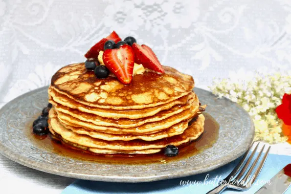 A plate of sourdough pancakes with syrup and fresh berries.