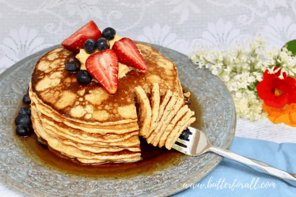 A stack of sourdough pancakes with syrup and fresh berries.