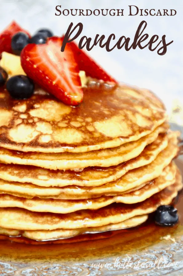 A stack of sourdough pancakes with syrup and fresh berries with text overlay.