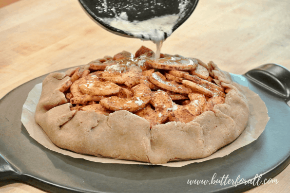 Pouring melted butter over the apple galette.