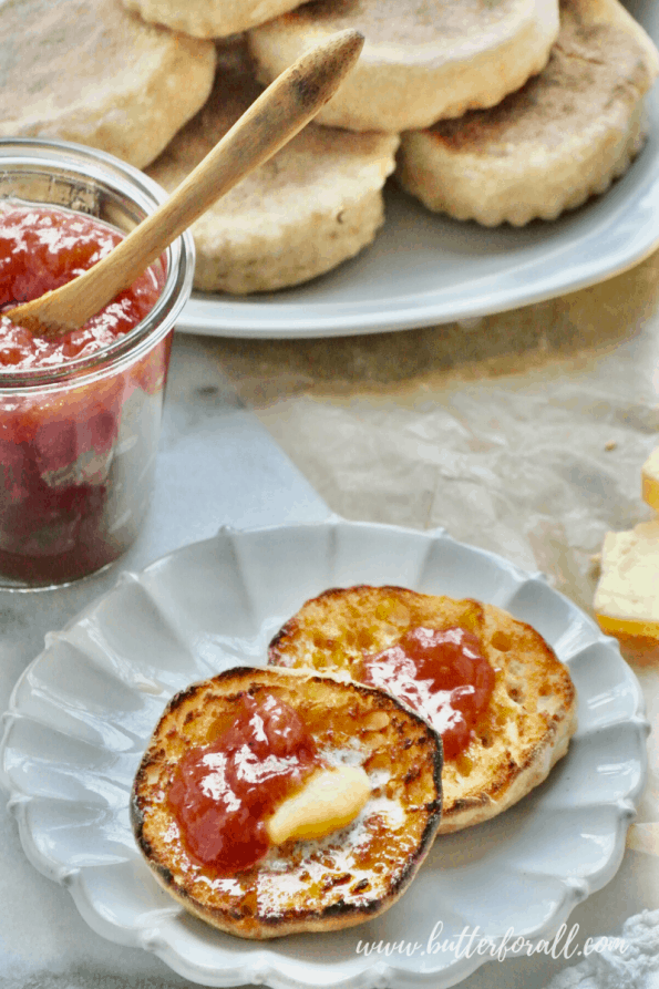 A close-up of stacks of English muffins with jam and butter.