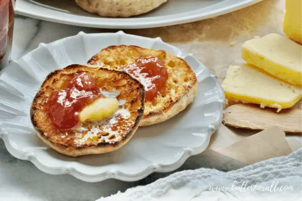 An English muffin spread with raw butter and jam.