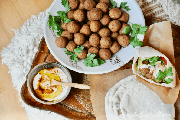 A bowl of falafel balls with pita and tahini.