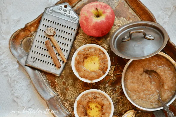 Bowls of hot buttered apple sauce on a tray with ingredients.