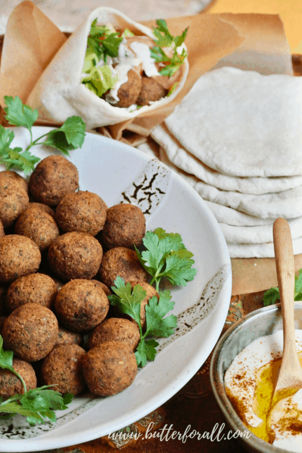 A bowl of falafel balls with pita and tahini.