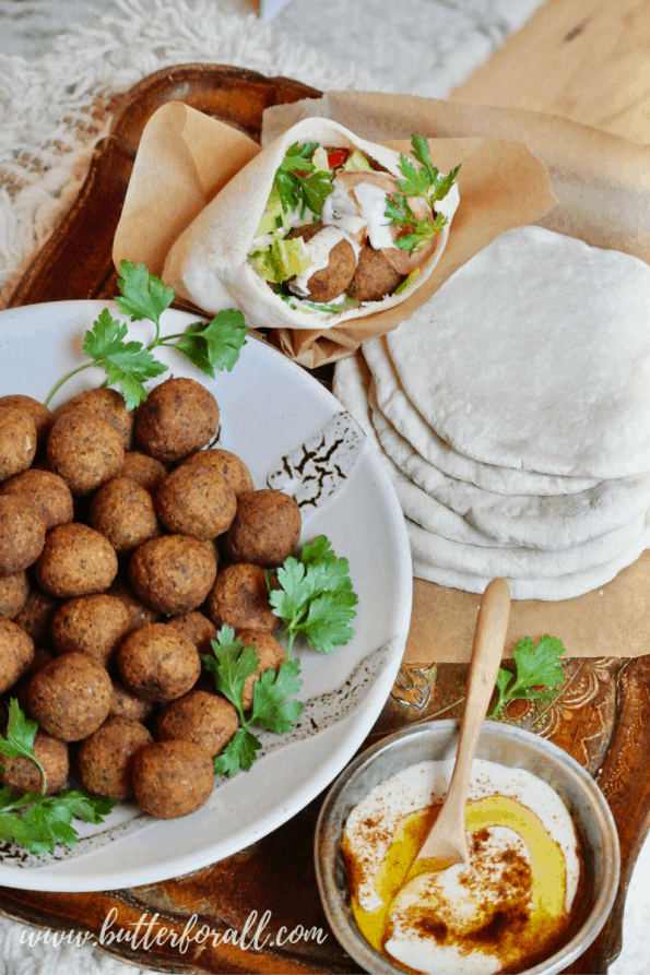 A pita stuffed with fried falafel balls, tahini, and veggies and a bowl of fried falafel balls.