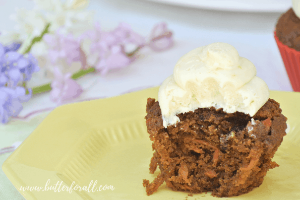 A coconut honey buttercream frosted cupcake with a bite taken out of it.