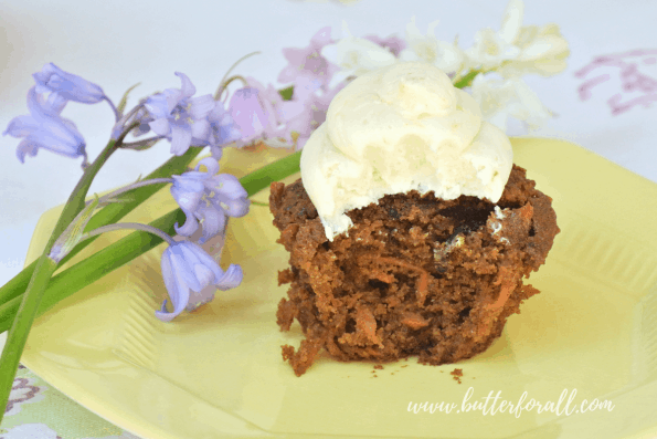 A coconut honey buttercream frosted cupcake with a bite taken out of it.