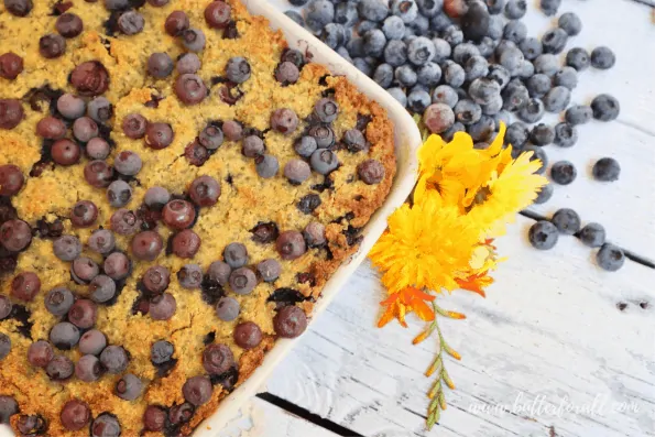 Image showing a pan of blueberry cornbread as a cake topped with fresh blueberries.