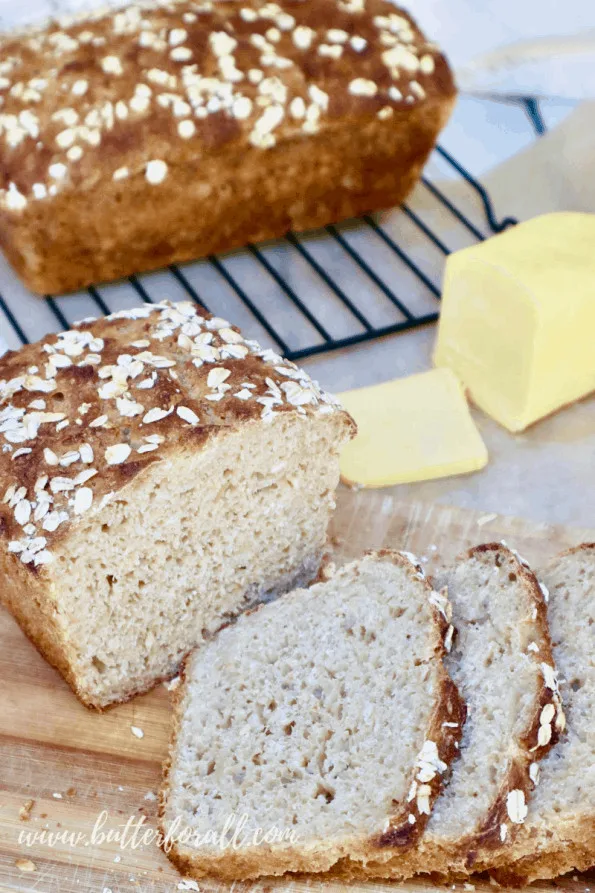 A thinly sliced loaf of buttermilk sourdough bread with real raw butter and a second loaf in the background. 