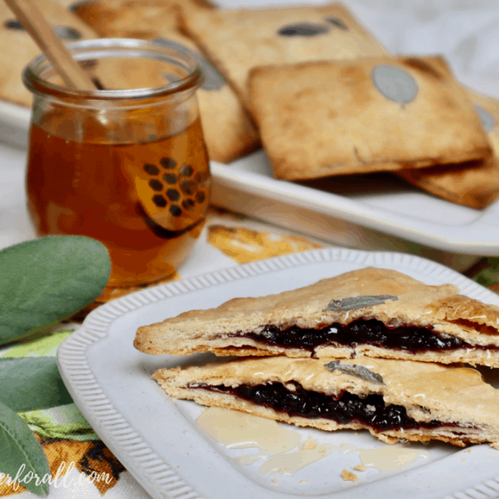 A plate with a perfectly brown toaster tart cut in half and showing the delicious blackberry filling.