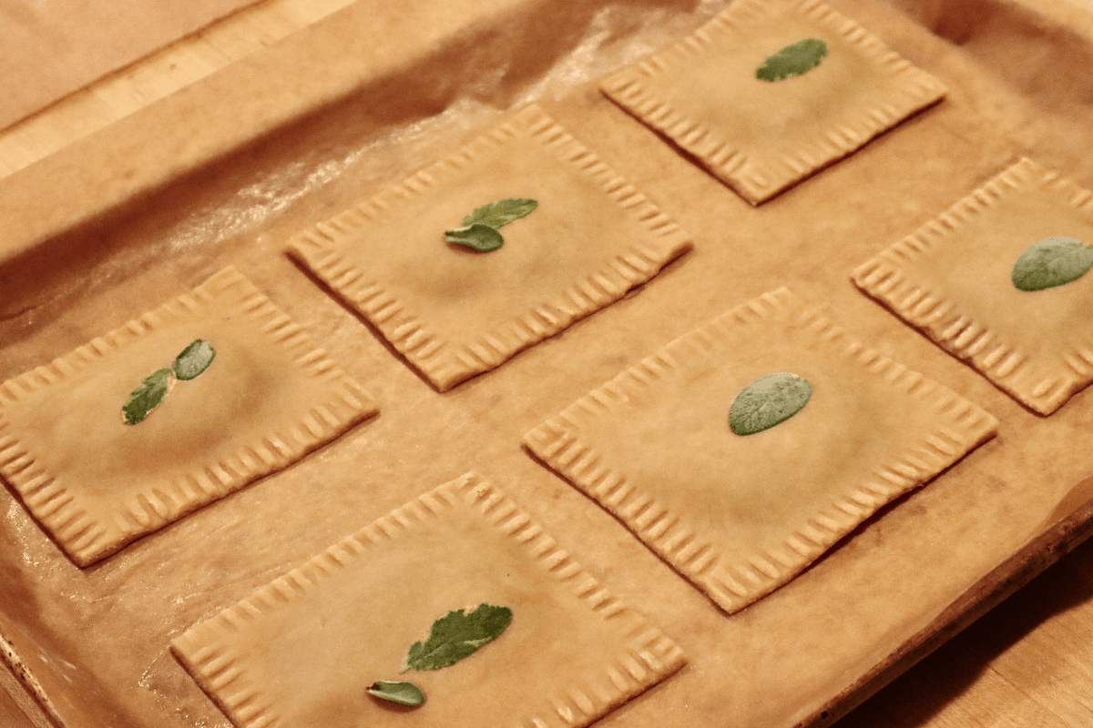 Six unbaked tarts on a parchment lined baking sheet.