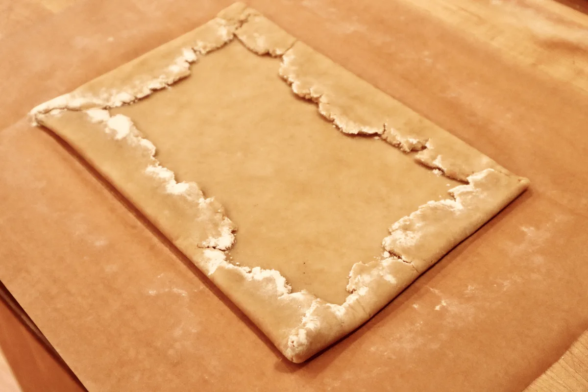 The jagged edges of the dough are folded over to make a tight rectangle.