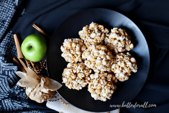 Plate of seven Cinnamon Apple Honey-Butter Caramel Popcorn Balls with festive decorations.