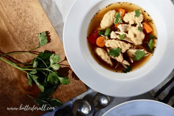 A bowl of Chicken and Sourdough Dumplings garnished with fresh parsley and sage. 