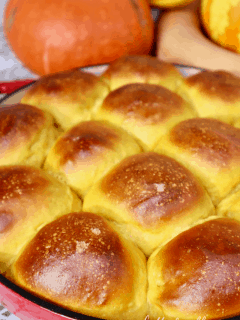 A large pan of golden brown, puffy, sourdough pumpkin rolls.