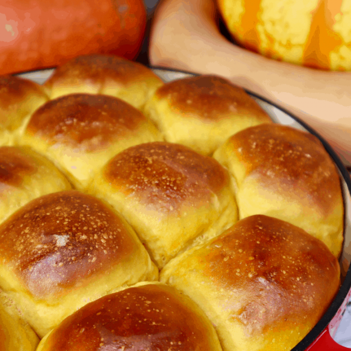 A large pan of golden brown, puffy, sourdough pumpkin rolls.