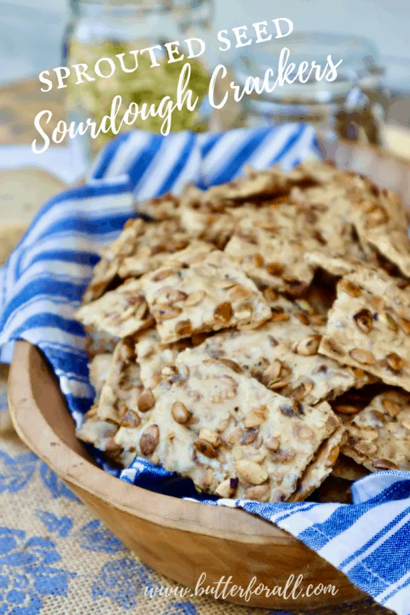 A bowl full of crispy, golden brown, seeded sourdough crackers with title text.