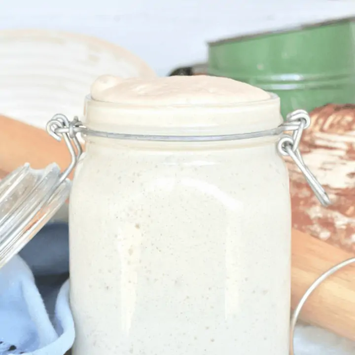 A large jar filled to the brim with bubbly sourdough starter.