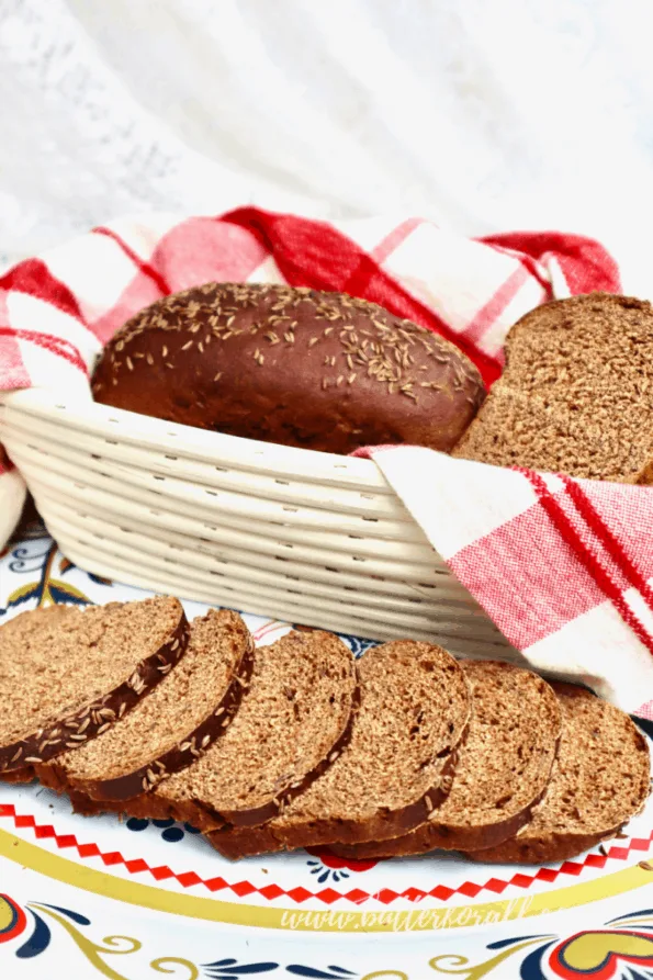 A beautiful tablescape with a basket of sourdough rye loaves and a platter of perfect rye bread slices.