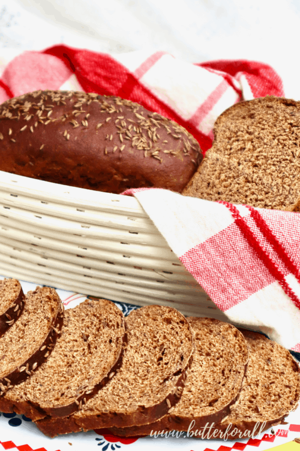 A basket and platter with two little loaves of dark sourdough rye bread.