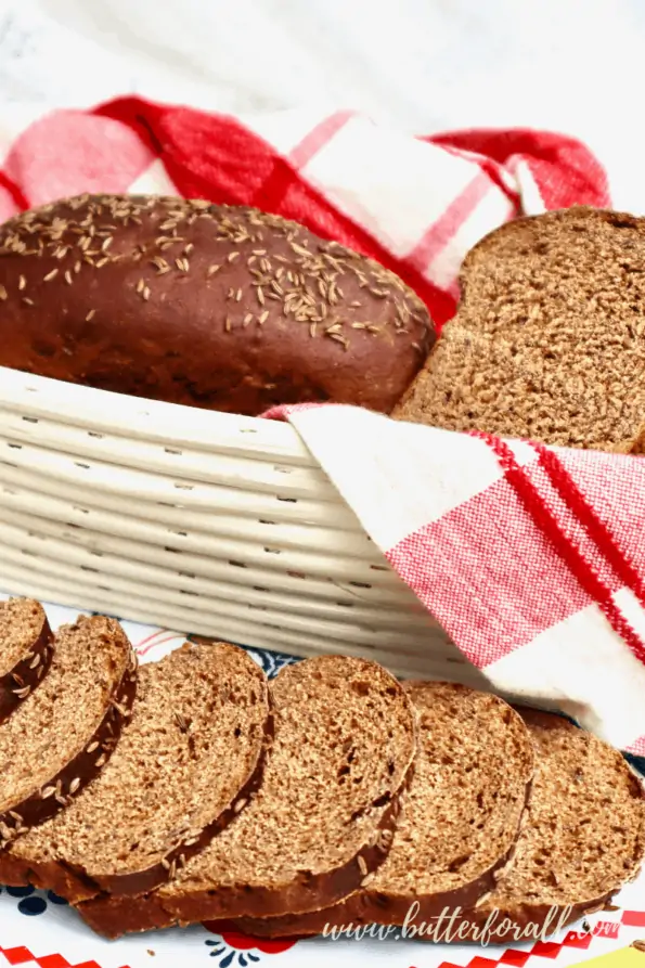 A basket and platter with two little loaves of dark sourdough rye bread.