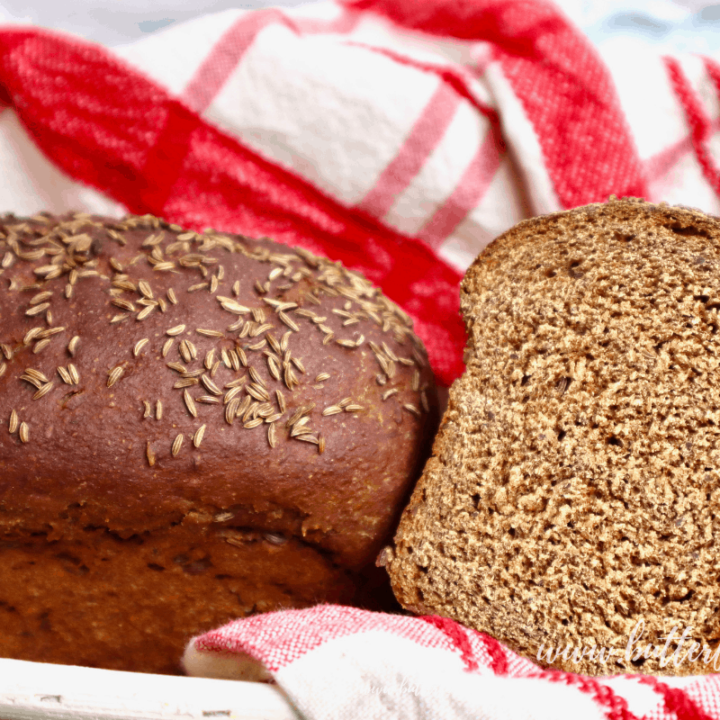 A basket of dark colored sourdough rye bread with caraway seeds on top.