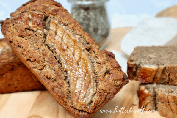 A golden brown loaf of chia seed and buckwheat banana bread with a caramelized banana on top.