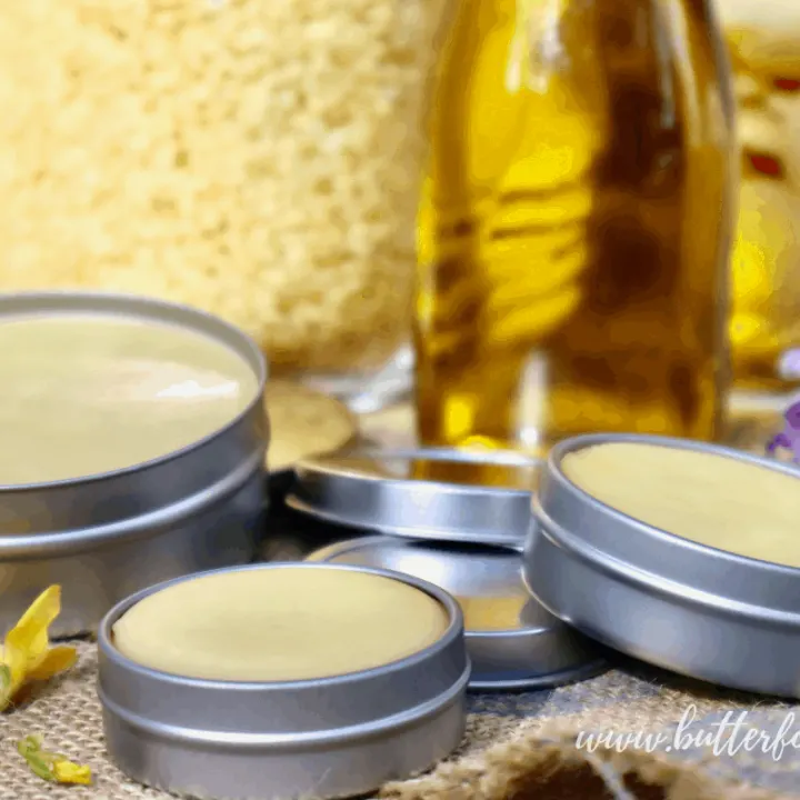 Different sized tins with solid golden salve made from beeswax, cocoa butter, and olive oil.