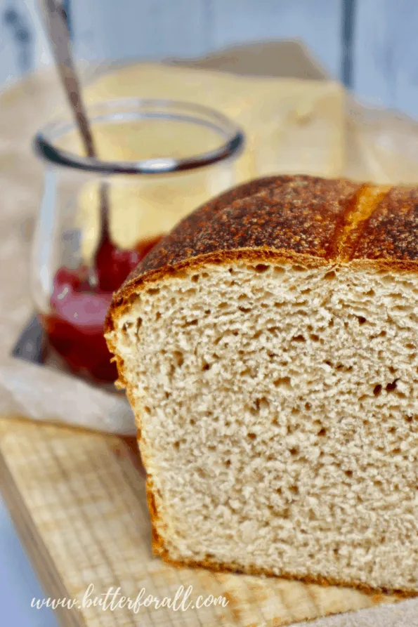 A half loaf of Kamut sourdough sandwich bread with fresh cultured butter and a jar of jam. 