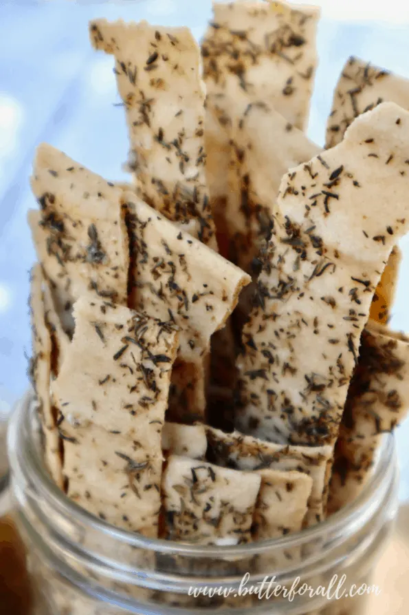 A jar full of long cassava crackers with herbs.