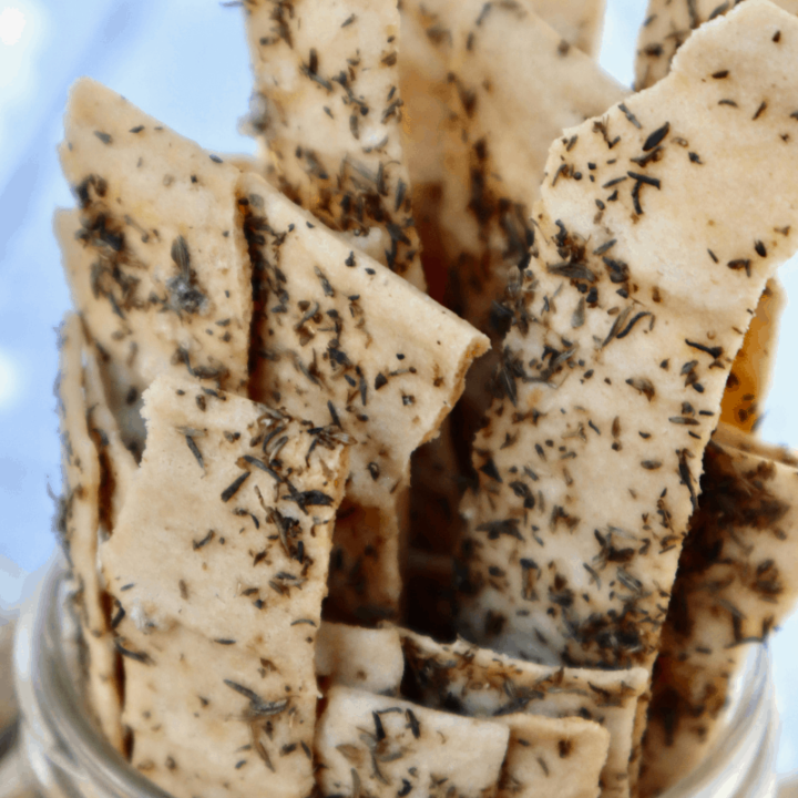 A jar full of long cassava crackers with herbs.