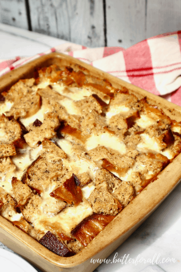 A casserole dish filled with herby cheesy sourdough bread pudding.