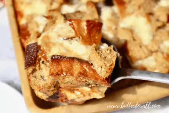 Scooping hot sourdough bread pudding from the pan.