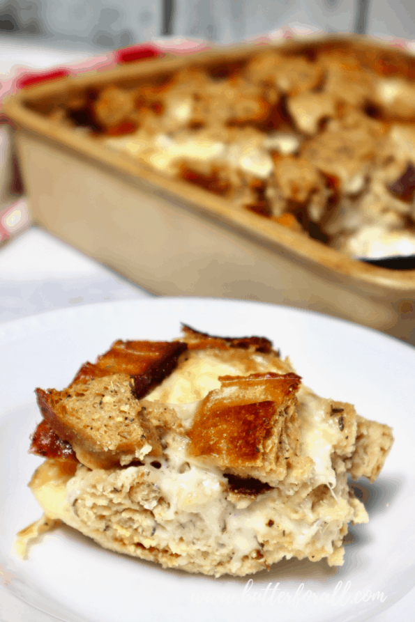 A serving of fresh sourdough bread pudding with casserole dish in the background.