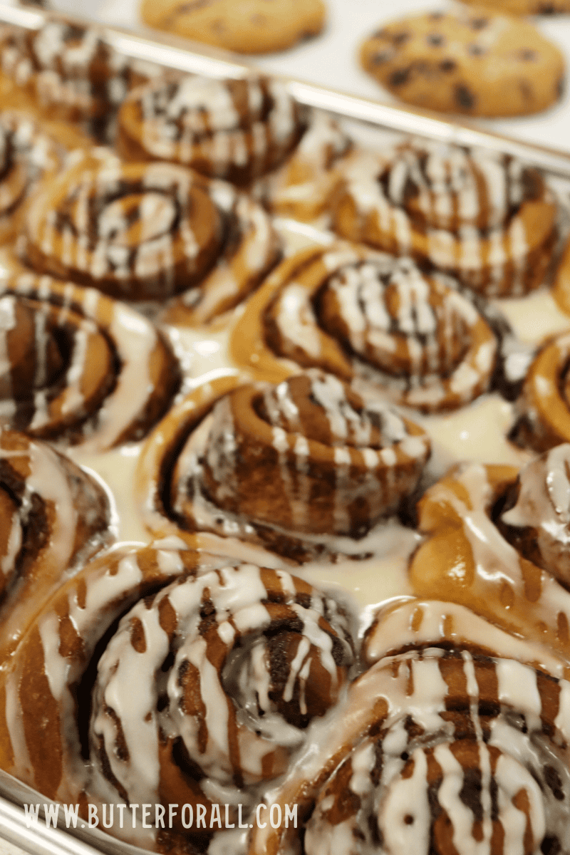 A pan filled to the brim with beautifully-rolled golden-brown brioche sourdough cinnamon rolls.