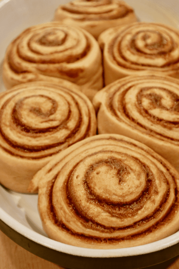 Fully proofed sourdough cinnamon rolls in a pan.