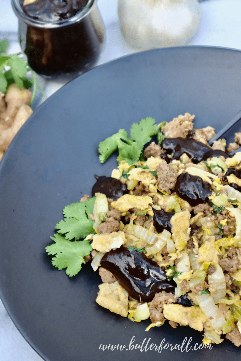 A bowl full of moo shu beef with black garlic plum sauce.