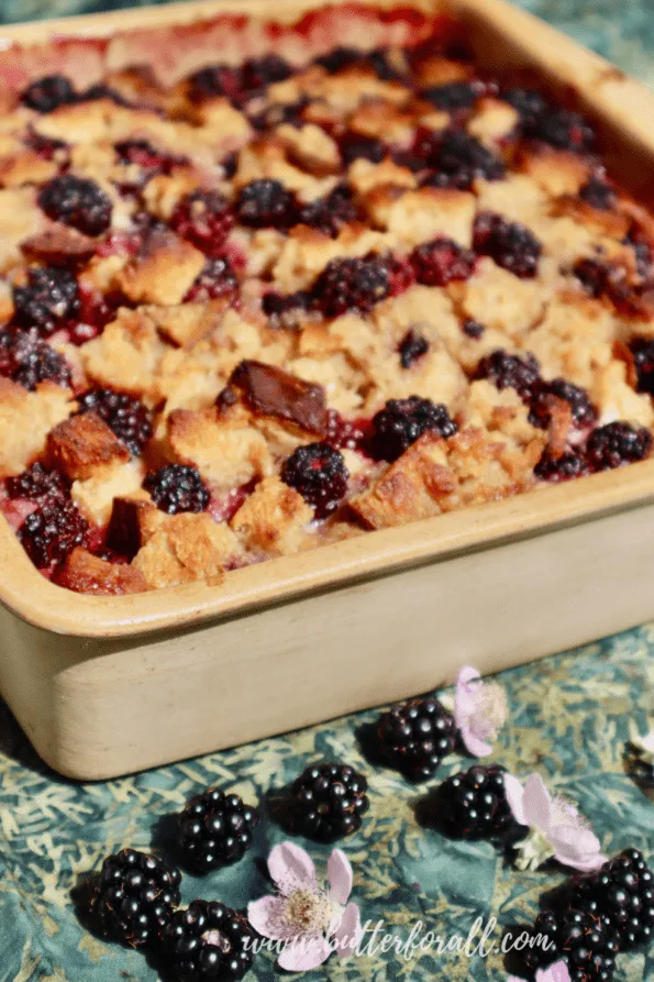 A ceramic pan filled with golden-brown blackberry sourdough bread pudding.