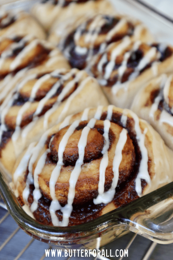 A close-up of perfectly formed sourdough cinnamon rolls with sugar glaze.